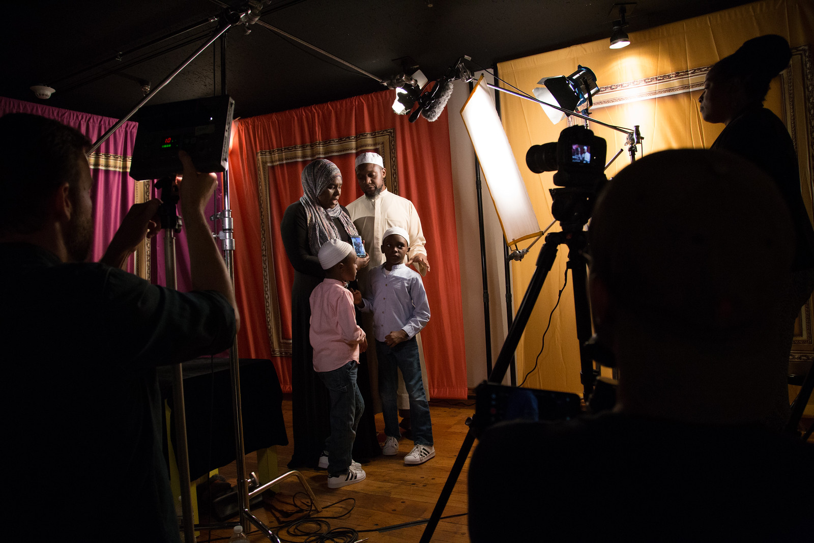 A mother, father, and their 2 children holding their family photograph with a camera crew recording