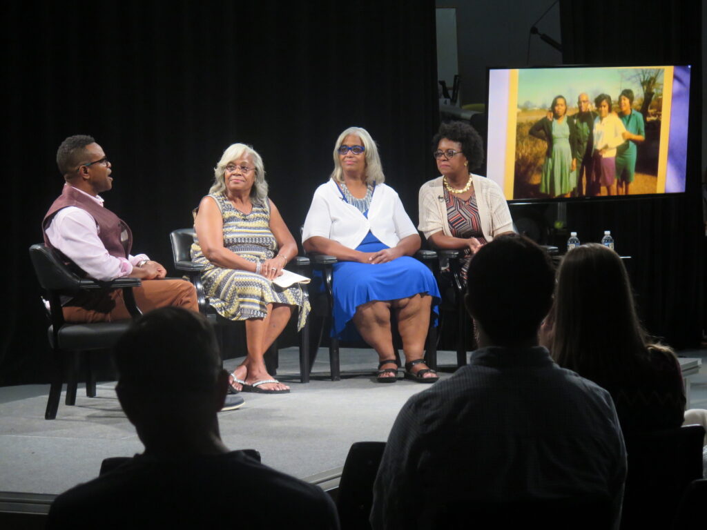 Thomas Allen Harris on stage talking with 3 women and an archival photograph on display