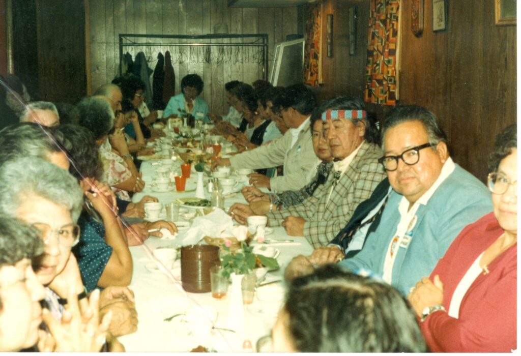 An archival color photograph of a large family sitting down for dinner in a restaurant